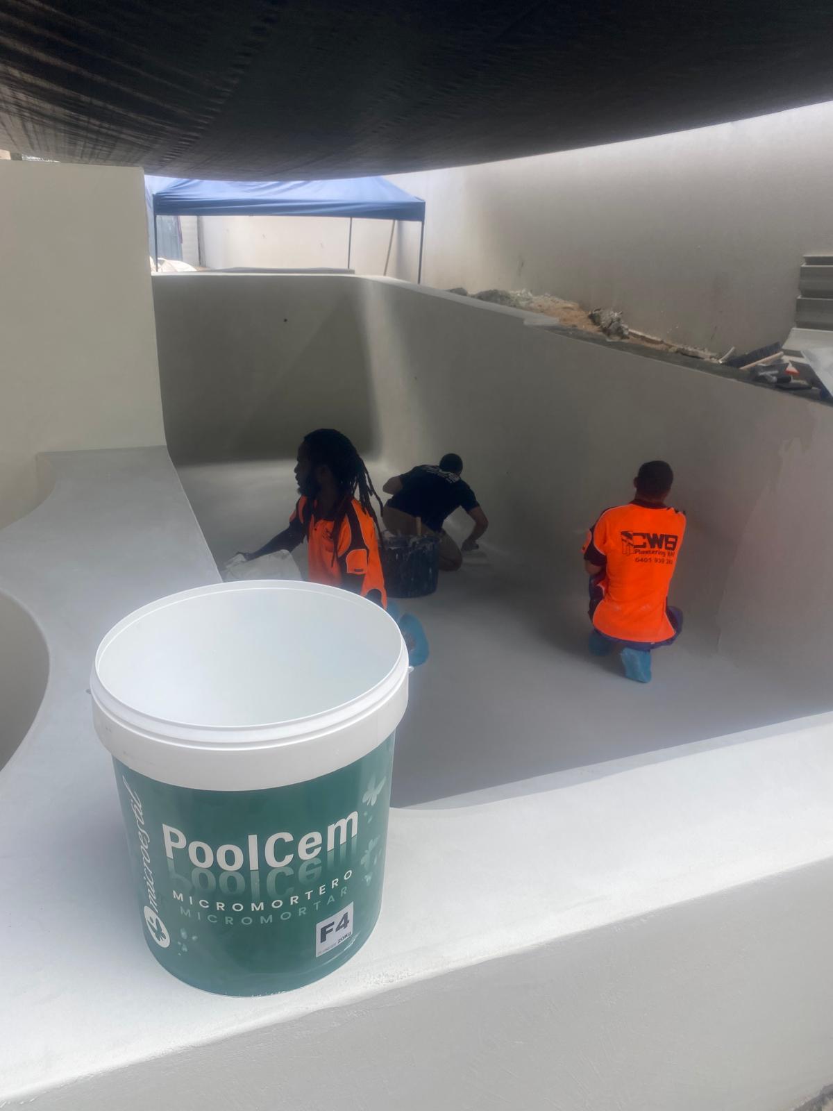 Crew applying PoolCem waterproof microcement inside an empty pool